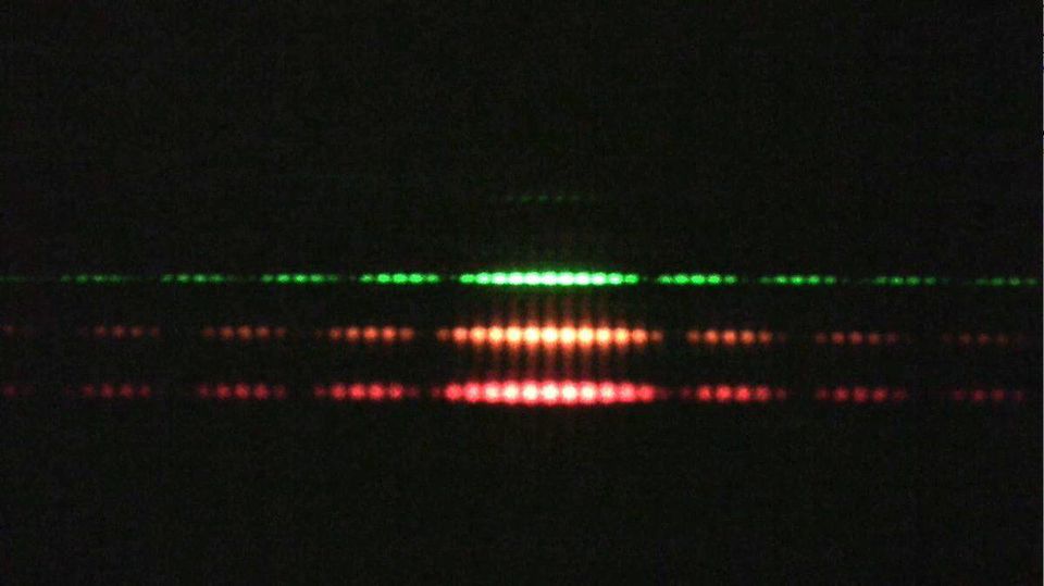 Double slit experiments performed with light produce interference patterns, as they do for any wave you can imagine. The properties of different light colors is understood to be due to the differing wavelengths of monochromatic light of various colors. Redder colors have longer wavelengths, lower energies, and more spread-out interference patterns; bluer colors have shorter wavelengths, higher energies, and more closely bunched maxima and minima in the interference pattern.